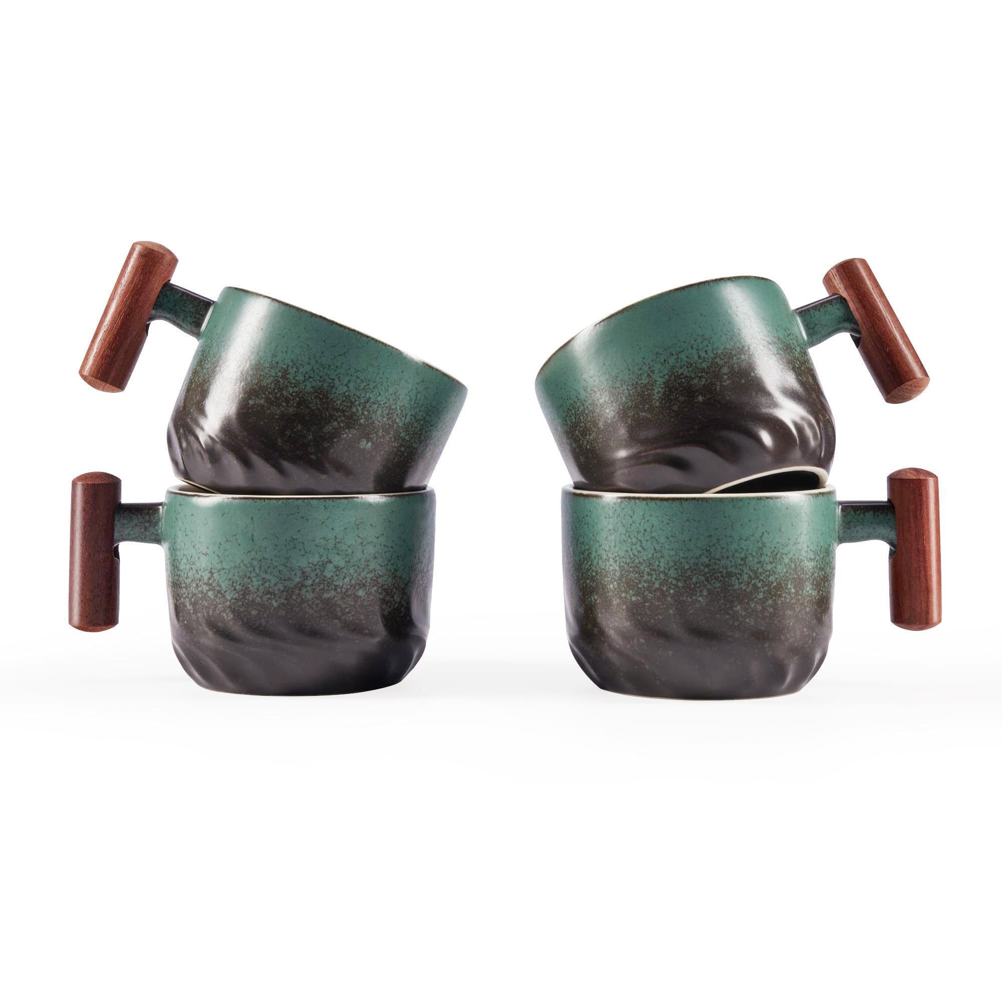 Four ceramic mugs with a dark green and black gradient glaze and brown wooden handles, arranged in two pairs on a white background.