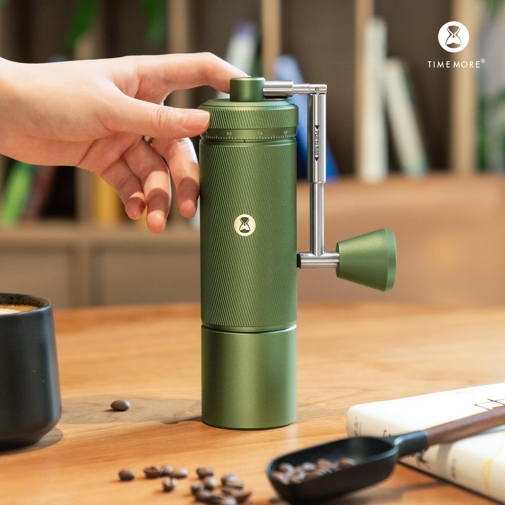 Green portable coffee maker on a wooden table with a blurred background