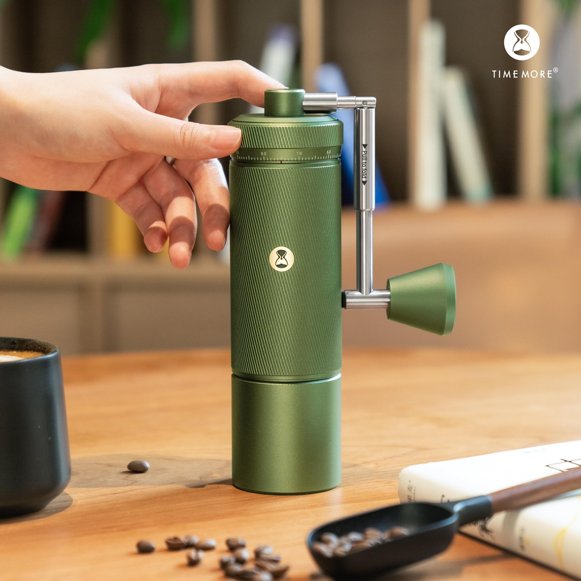 Green portable coffee maker on a wooden table with a blurred background