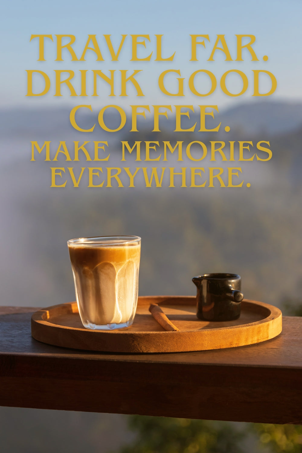 A glass of layered coffee drink and a small dark cup sit on a round wooden tray on a balcony railing, with large yellow text above reading 'TRAVEL FAR. DRINK GOOD COFFEE.