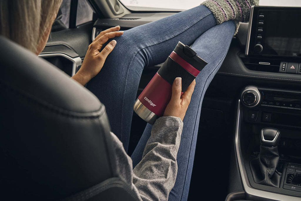 Person holding a red and black cup in a car, with a focus on the cup.