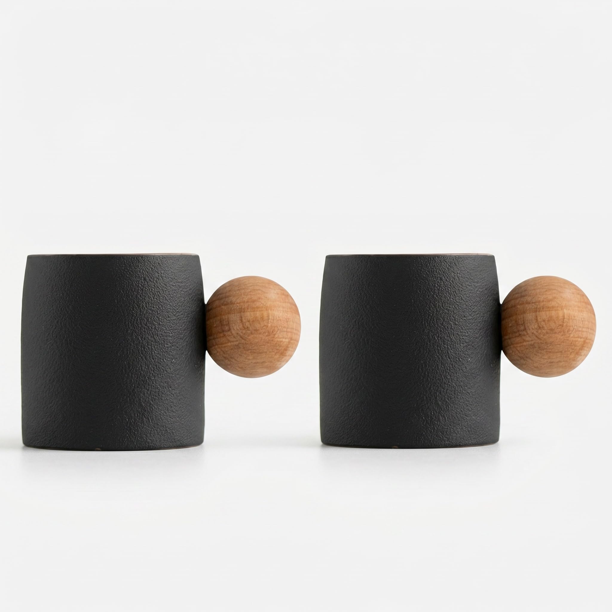 Two matte black ceramic mugs with round natural wood handles, shown side by side on a clean white background.