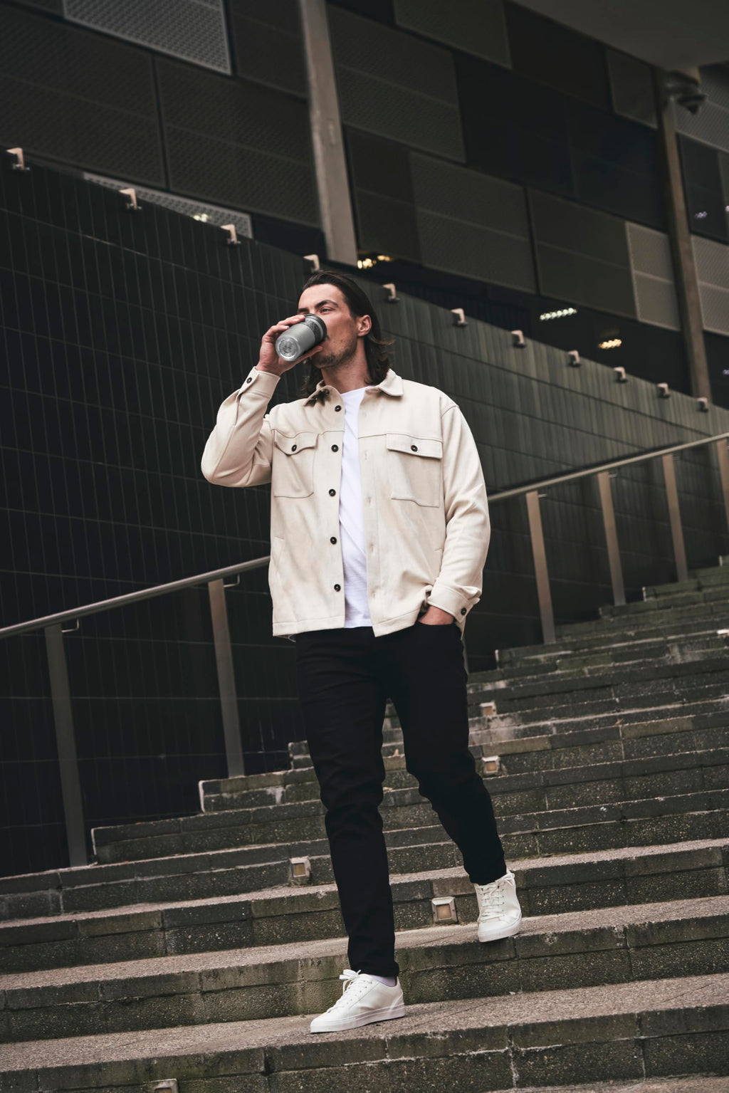 Man drinking from a bottle on a set of stairs in an urban setting