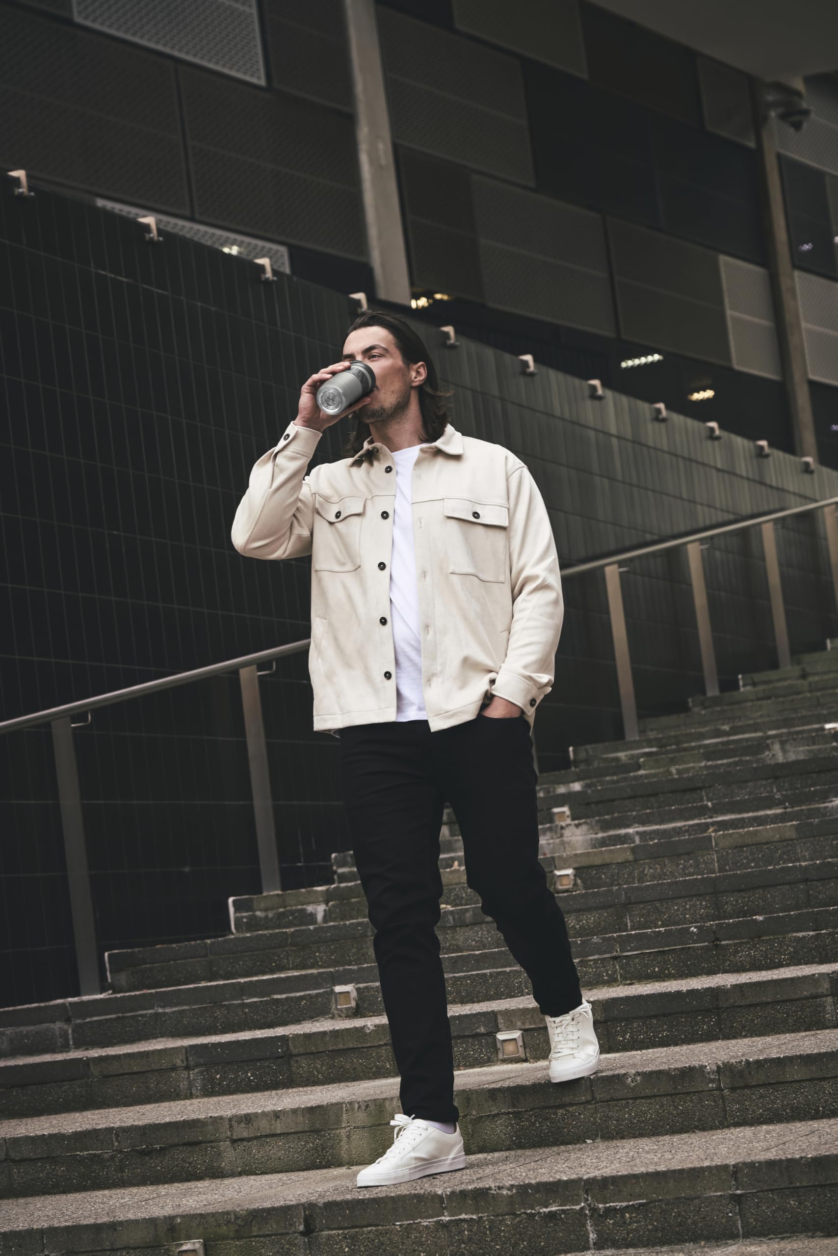 Man drinking from a bottle on a set of stairs in an urban setting