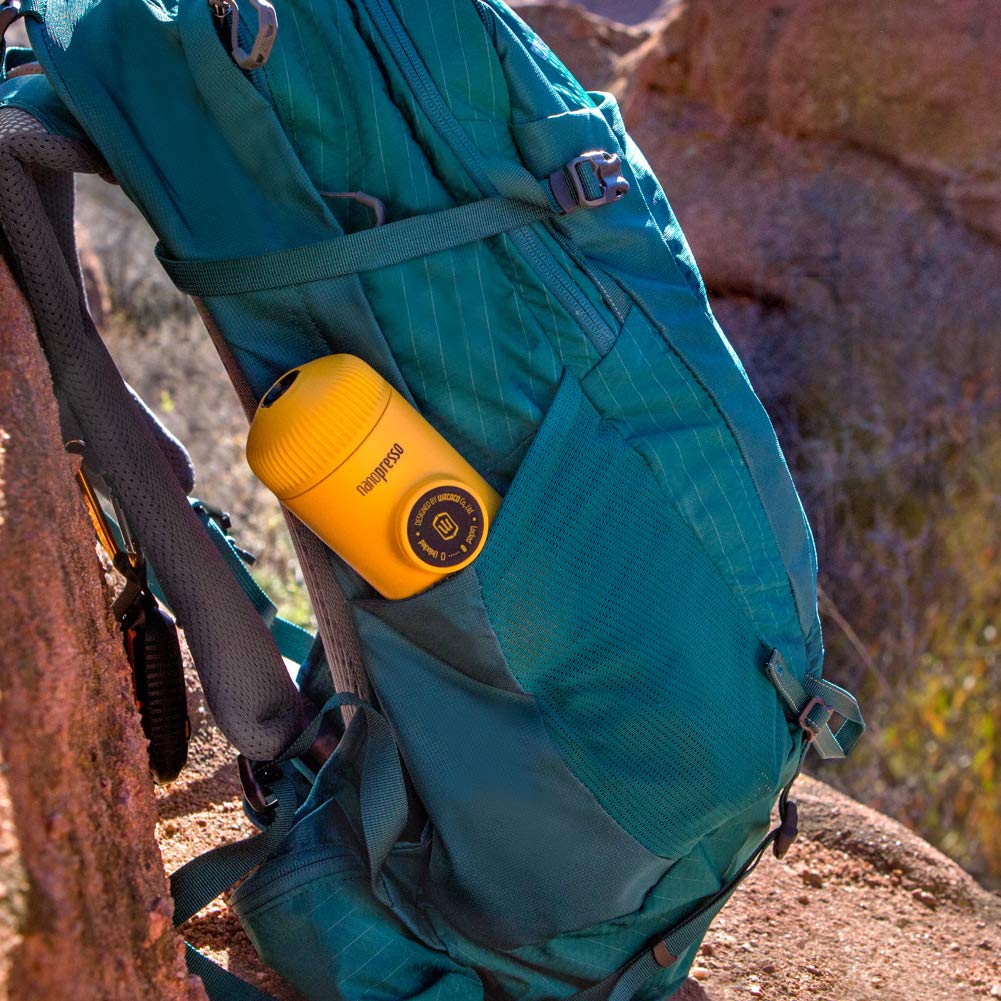 Teal backpack with a yellow hydro flask attached, outdoors.