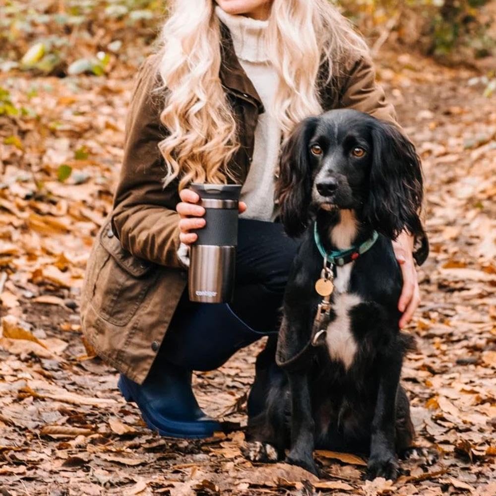 Person with a dog in an autumn setting holding a thermos.