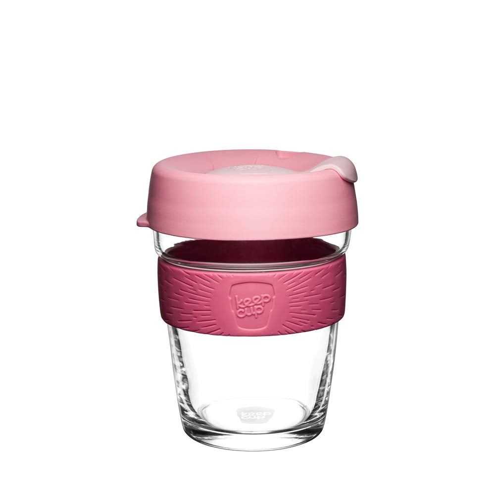 A reusable glass travel cup with a translucent pink lid, a textured pink silicone sleeve, and a clear glass body, shown on a plain white background.